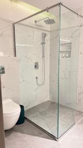 a bathroom with a glass shower with a toilet at Amaris Hotel in Al Ḩamrāʼ