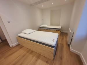 two beds in a small room with wooden floors at Appartement entier in Izeaux
