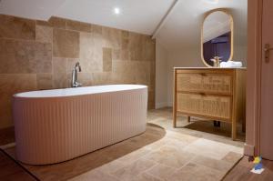 een badkamer met een bad, een wastafel en een spiegel bij Dodoterla - BoisBlanc in Sainte-Rose +18 foto's