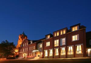 a large brick building with a church in the background at Hotel von Euch in Meppen