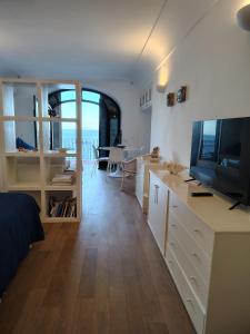 a bedroom with a television and a living room with a table at Casa vista Faraglioni Capri in Capri