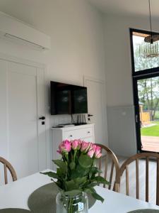 Un jarrón de flores rosas sobre una mesa. en Lakeview Houses, en Gil Mały