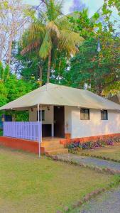 una pequeña casa blanca con una sombrilla grande en Hiranya Nature Retreat, en Daulatābād