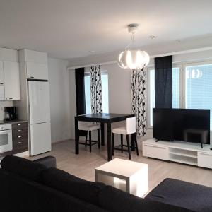 a living room with a black table and a kitchen at Northern 2-room apartment with Sauna and Garage in Rovaniemi