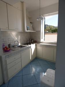 a white kitchen with a sink and a window at Ella House in Ischia +21 photos