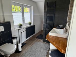 a bathroom with a white toilet and a sink at Ferienhaus Neeborg in Zetel +20 photos
