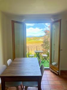 a dining room with a table and a view of a patio at Duplex provençal au cœur des vignes à 5 min du centre-ville in Sablet