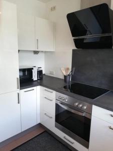 a kitchen with white cabinets and a stove top oven at Himmelthal Apartment in Eschau