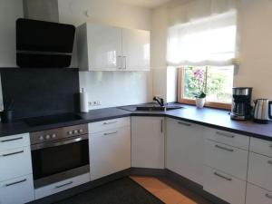 a kitchen with white cabinets and a black counter top at Himmelthal Apartment in Eschau