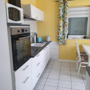 una cucina con mobili bianchi e un forno a microonde di Ferienwohnung Stefanie am Frankenbach a Bad Breisig