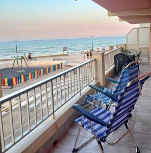 2 blaue Stühle auf einem Balkon mit Blick auf den Strand in der Unterkunft De frente al mar in Sueca