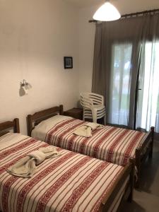 a bedroom with two beds and a chair and a window at Lagomandra Nakis in Lagomandra