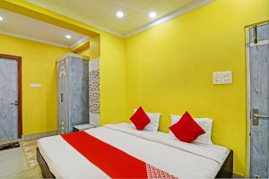 1 dormitorio con 1 cama con paredes amarillas y almohadas rojas en Hotel O Annapurna Plaza, en Thākurdwari 26 fotos más