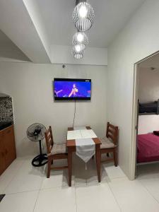 a dining room with a table and a tv on the wall at JLC Crib in Naga +6 photos