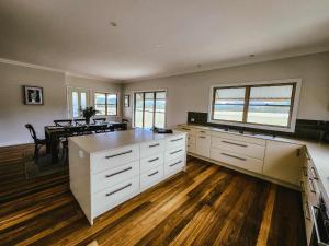 a kitchen with white cabinets and a dining room with a table at Willow Lodge in Junabee +40 photos