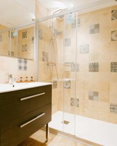 a bathroom with a glass shower with a sink and a shower at Les Jardins de Falguière in Saint-Jean-du-Gard