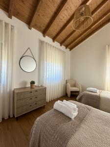 1 Schlafzimmer mit 2 Betten, einem Spiegel und einem Stuhl in der Unterkunft Casas da Pereira in Barcos + 51 Fotos