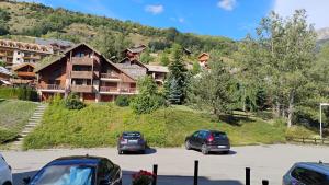 zwei Autos auf einem Parkplatz vor einem Gebäude geparkt in der Unterkunft Cosy studio in Serre Chevalier in Saint-Chaffrey