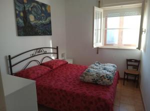 een slaapkamer met een rood bed en een raam bij Casa al mare in centro a 100 metri dalla spiaggia con terrazza in Torre Santa Sabina