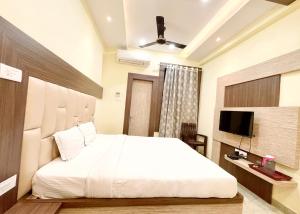 a bedroom with a large white bed and a television at V - NEW HOTEL - ND & P PREMIUM - The Point of Kashi - Near Kashi Vishwanath Temple !! - Free Wi-Fi and Parking Facilities # Fully Air Conditioned Hotel - Best Hotel In Varanasi in Rāmnagar +11 photos
