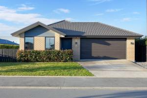 a house with a garage on a street at Queen Bed with Private Bath TV kitchen access and one Parking in Rolleston