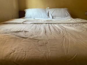 1 cama no hecha con sábanas y almohadas blancas en Chikawaga Lodge, en Blantyre 2 fotos más