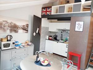 a kitchen with white cabinets and a table and a microwave at La petite maison de Claire in Cuneo