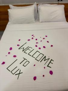 a bed with pink flowers on it with the words wanting hate at Lux Hotel Mathiveri in Mathiveri