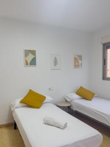 two beds with yellow pillows in a room at Apartamento San Diego 1 - Almyra Inmobiliaria in Los Alcázares