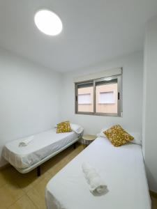 two beds in a room with a window at Apartamento San Diego 1 - Almyra Inmobiliaria in Los Alcázares
