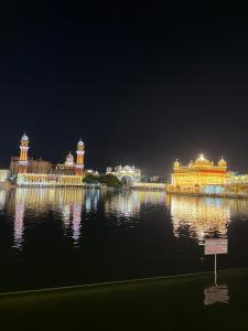a view of a large lit up palace in the water at night at Hotel KABIR ROYAL in Amritsar