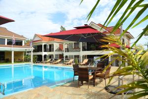 a pool with a table with chairs and an umbrella at SixPoint Victoria in Kisumu