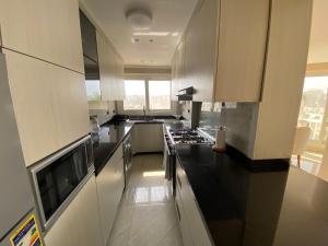 a kitchen with white cabinets and black counter tops at Heliopolis Ultra Luxury Panoramic Apt Near Cairo Airport in Cairo