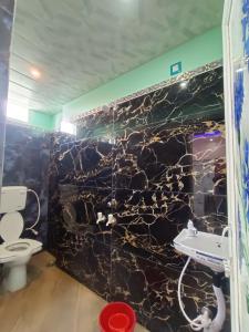 a bathroom with a black marble wall with a toilet at Mayapur Yatri Nivas in mayapur