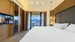 a bedroom with a large white bed and a balcony at MuYun Villa Lijiang in Lijiang