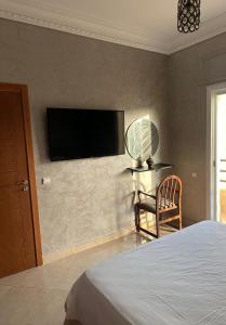 a bedroom with a tv on the wall and a chair at Appartement azla plage in Oulad Akkou