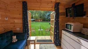 a living room with a couch and a television in a log cabin at Snowdrop Cabin Retreat dog friendly peaceful in Huttoft