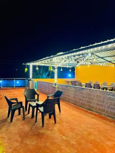 un groupe de chaises et de tables sur une terrasse la nuit dans l'établissement Eagle villa, à Kārli