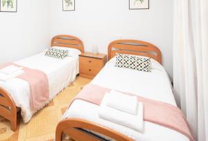 two beds in a room with white walls at AG Piso Isabema a 400m del centro de Carballo in Carballo