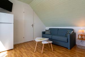 a living room with a blue couch and a table at Le Sea Bird draps parking piscine in Arzon