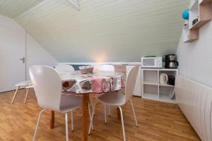 a dining room with a table and white chairs at Le Sea Bird draps parking piscine in Arzon