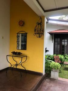 a yellow wall with a table in front of a house at Katys Lodge in Ja-Ela