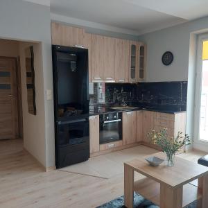 a kitchen with a black refrigerator and wooden cabinets at Apartament ZARA Self Check In in Rzeszów +5 photos