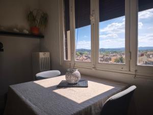 Una mesa con un jarrón sobre una mesa con una ventana. en Appartement Mistral vue imprenable, en Carcassonne