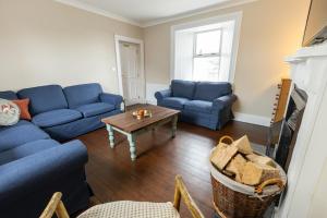 a living room with blue couches and a coffee table at Making Tracks Farm House in Laois