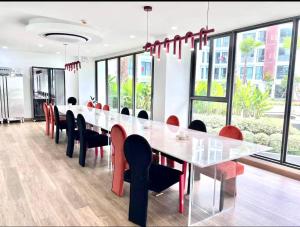 un comedor con una mesa larga y sillas rojas en The one condo chiang mai, en Chiang Mai
