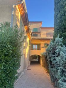 an alleyway leading to a building with bushes at Duplex provençal au cœur des vignes à 5 min du centre-ville in Sablet