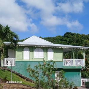 ラ・トリニテにあるLa Maison Verteの白いドアとバルコニー付きの緑の家