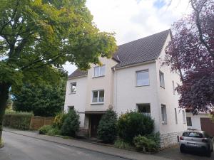 a white house with a car parked in front of it at Ferienwohnung am Kurwald, Nähe Kliniken, 88qm, Parkplatz in Bad Lippspringe