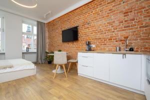 a bedroom with a brick wall and a bed and a kitchen at Central Lux Apartment - Heart of the Old Town Check In 24h in Wrocław